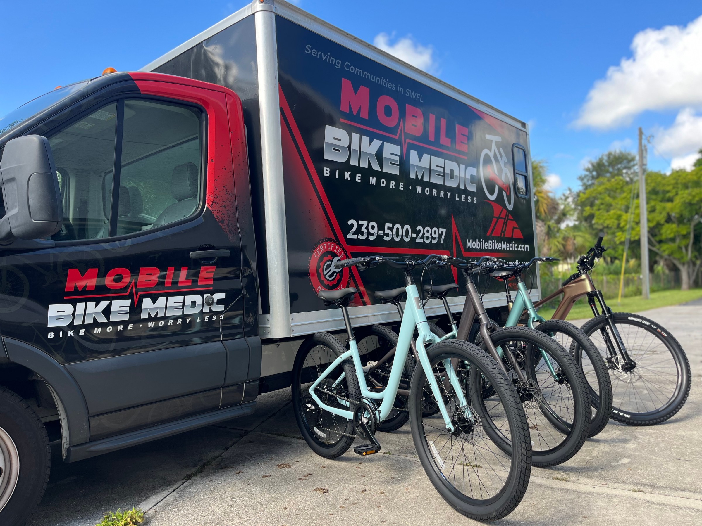Mobile bike service van with three bicycles parked in front on a sunny day.