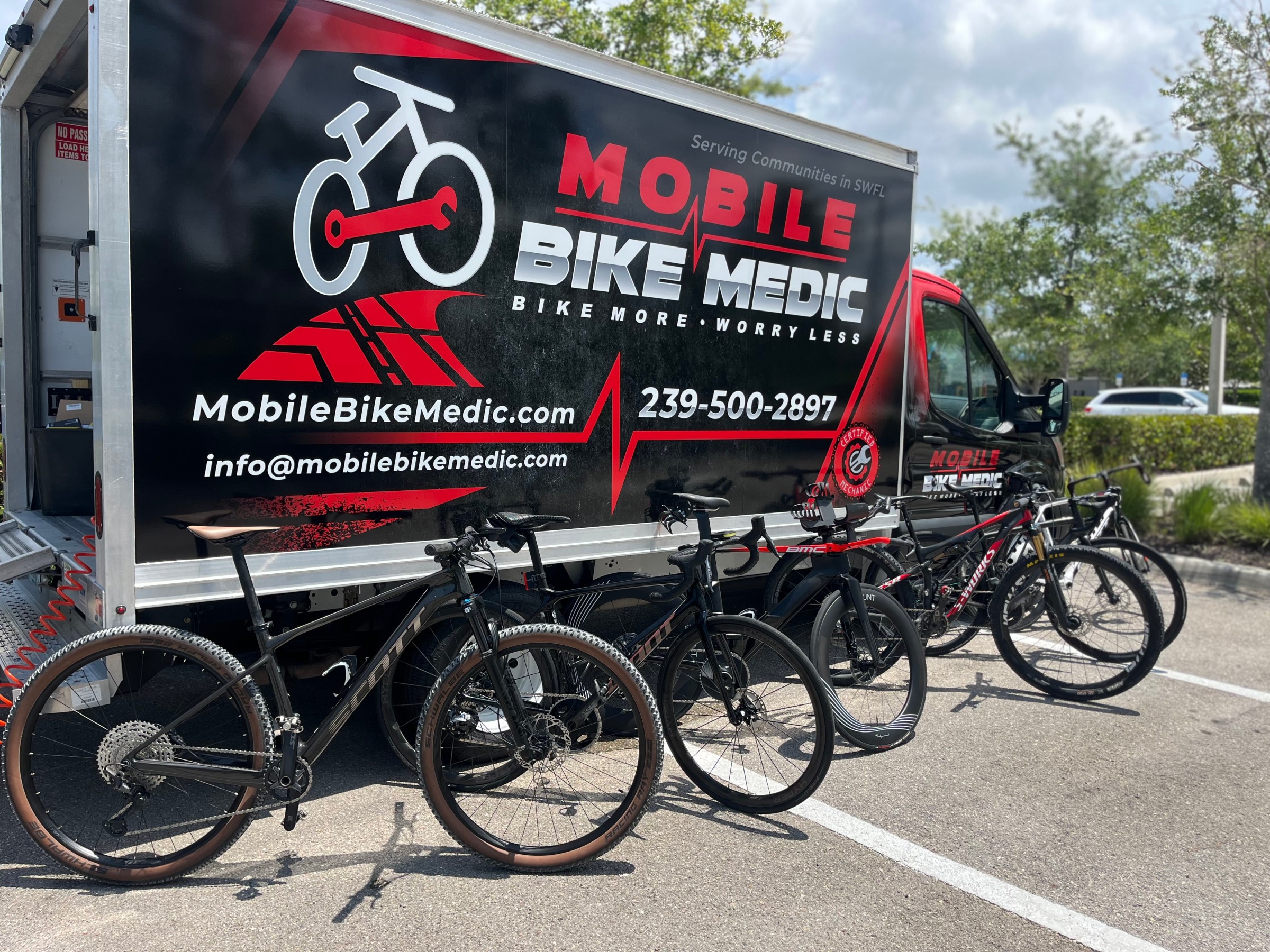 Mobile bike repair truck with multiple bicycles parked in front.